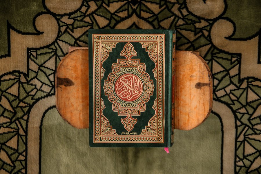The Holy Quran on a wooden stand over a prayer rug