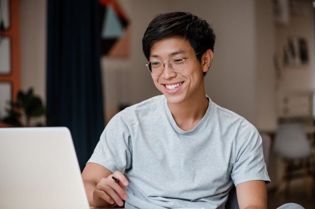 Smiling student taking an online Arabic lesson on his laptop